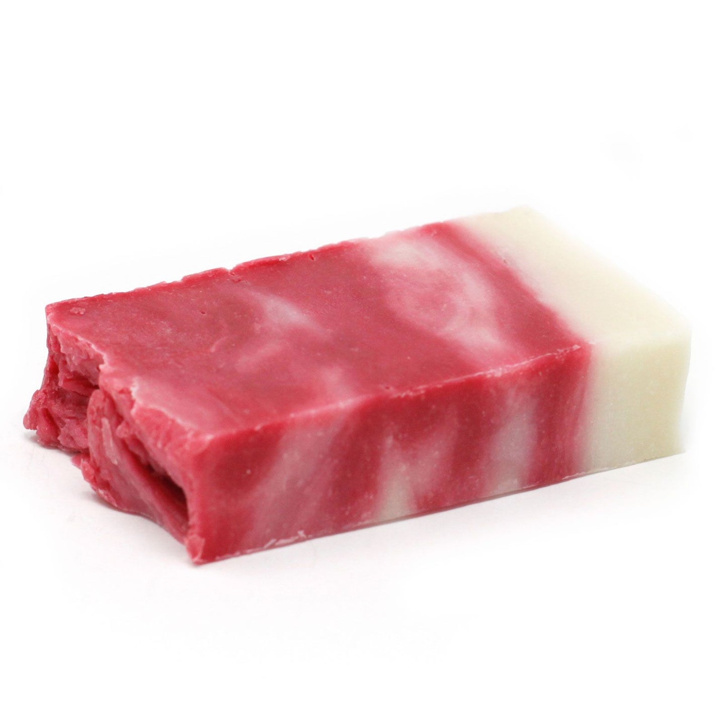 Handcrafted textured pink and cream olive oil soap slice with dried botanicals on top.