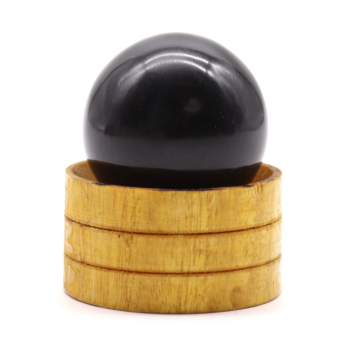 A polished dark tourmaline gemstone sphere resting on a small wooden stand, showing natural crystal textures.