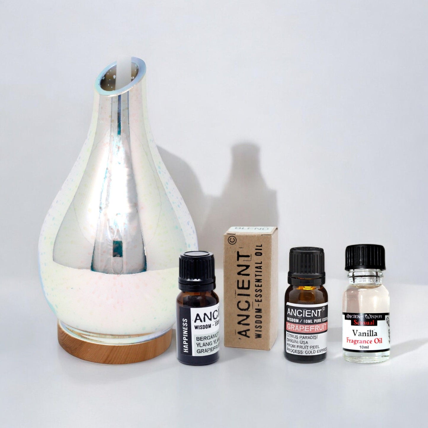 Elegant white ultrasonic aroma diffuser set with essential oils in a minimalist home setting.