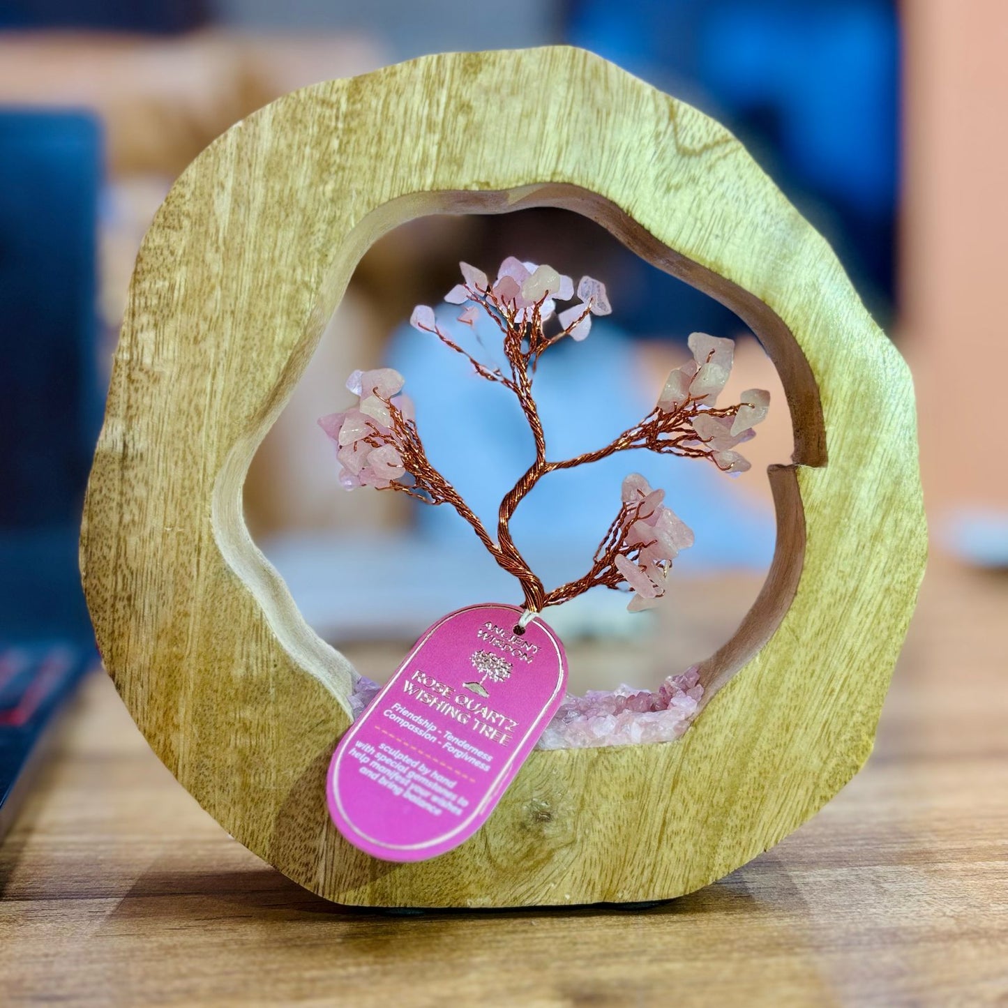 Delicate Rose Quartz crystal chip tree hand-wired inside a circular mango wood ring frame.