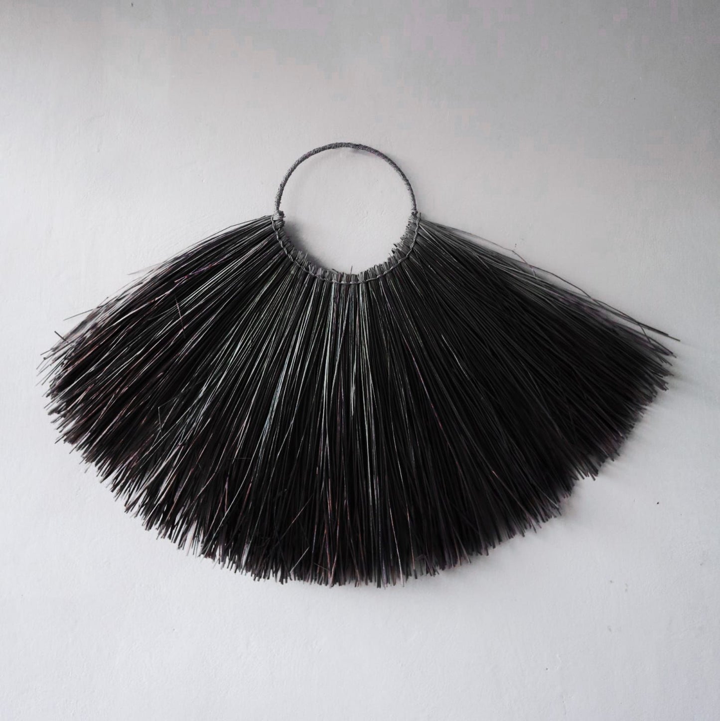 Large decorative wall fan made from black woven seagrass with a natural textured finish.