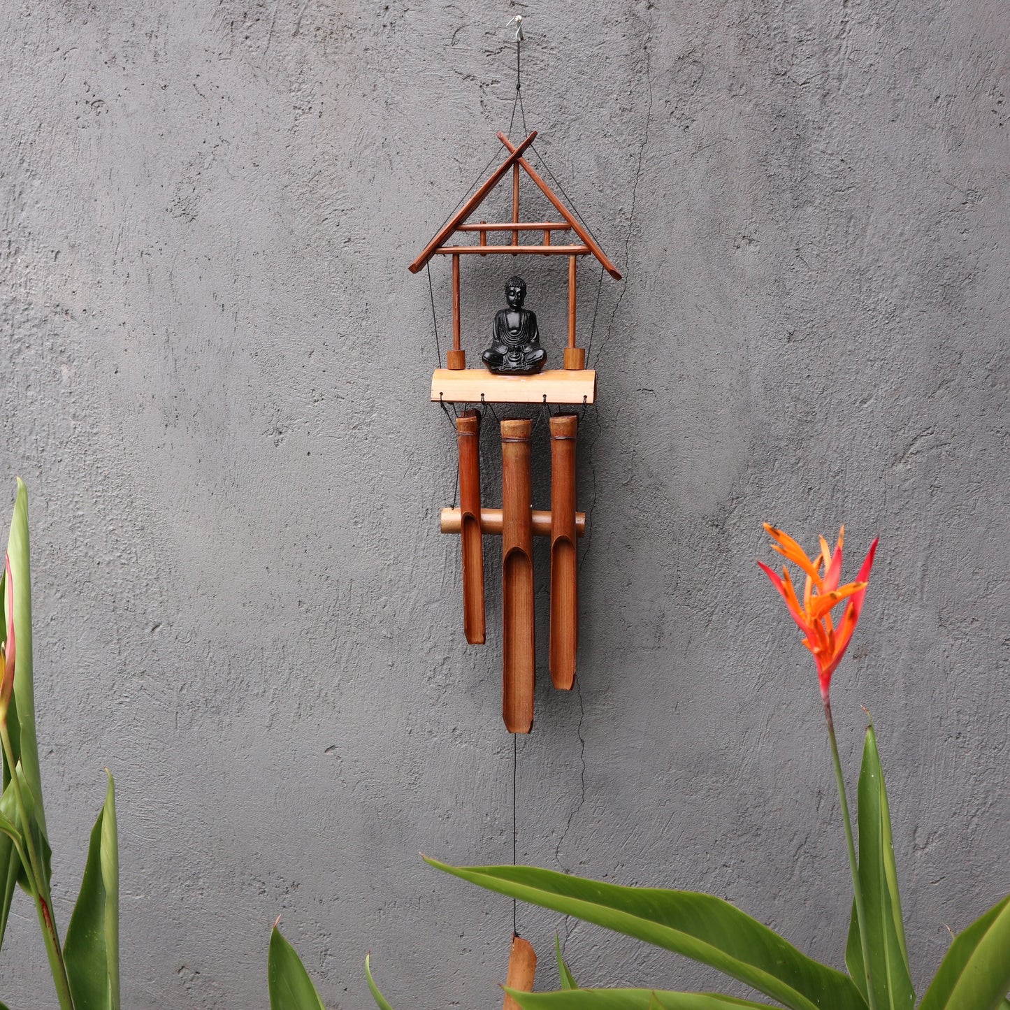 Handcrafted natural finish bamboo windchime with six tubes and a decorative black Buddha figure hanging at the centre.