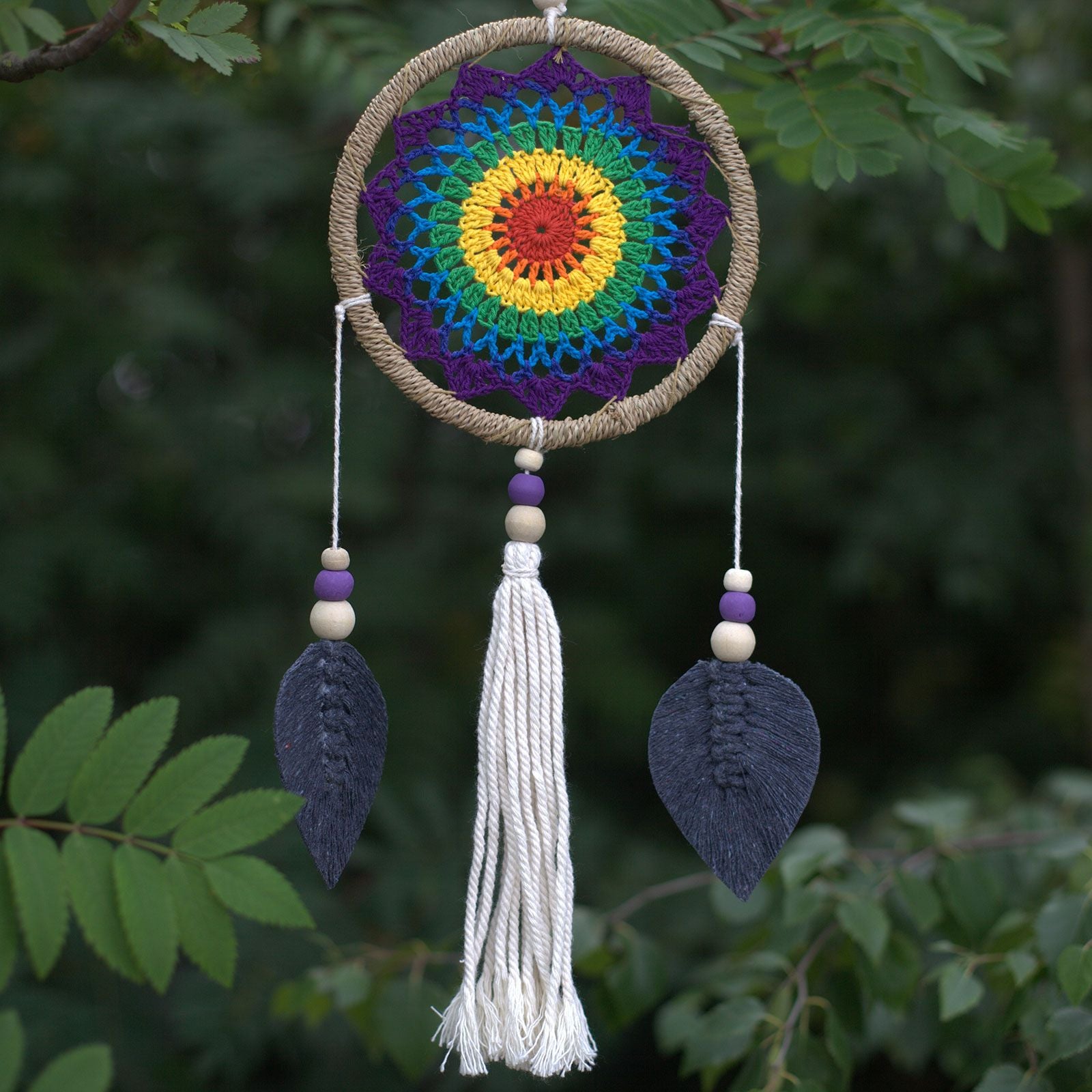 Medium-sized handmade dream catcher with a vibrant rainbow web and natural hanging elements, no feathers.