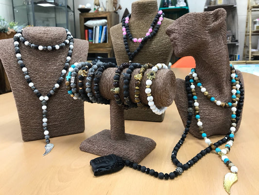 Hamsa necklace featuring pink and black gemstone beads, silver flowers, and porous black lava stone on a delicate chain.