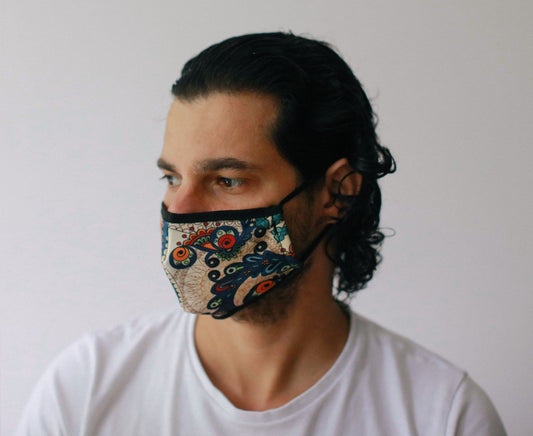 Adult-sized reusable fabric face mask featuring a stylish golden leaves pattern on a dark background.