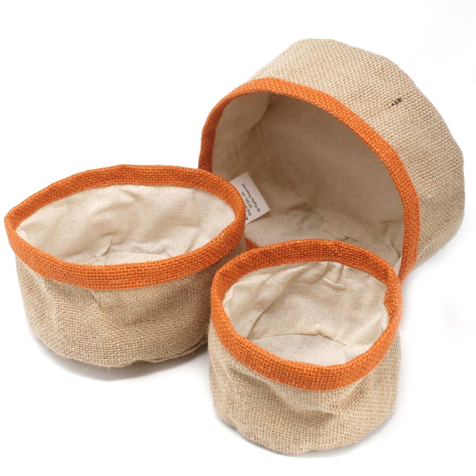 Three nested turmeric orange natural jute storage baskets with cream cotton lining in varying sizes.
