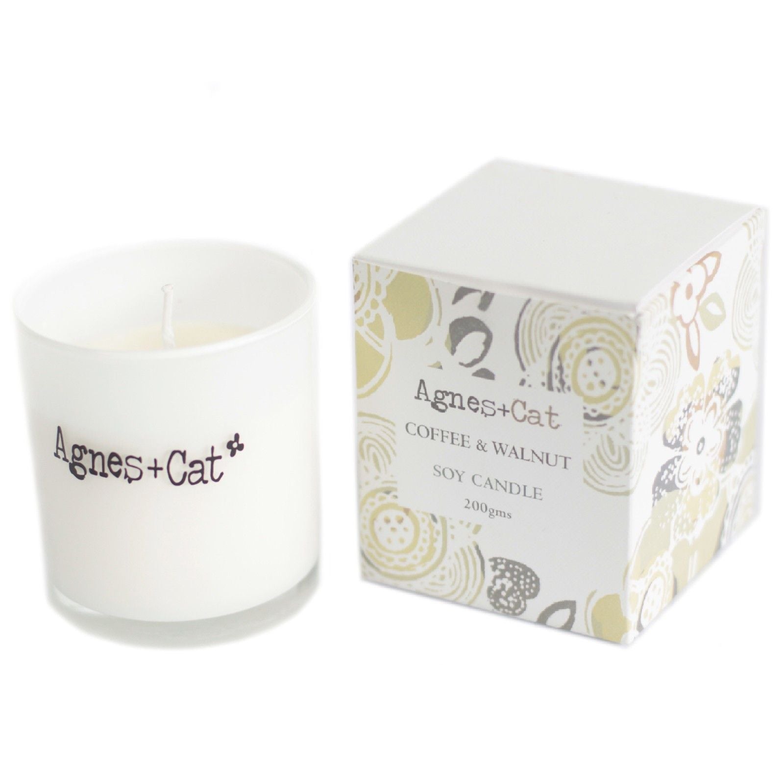 Small cream-coloured soy wax votive candle in a glass jar with a minimalist label on a wooden surface.