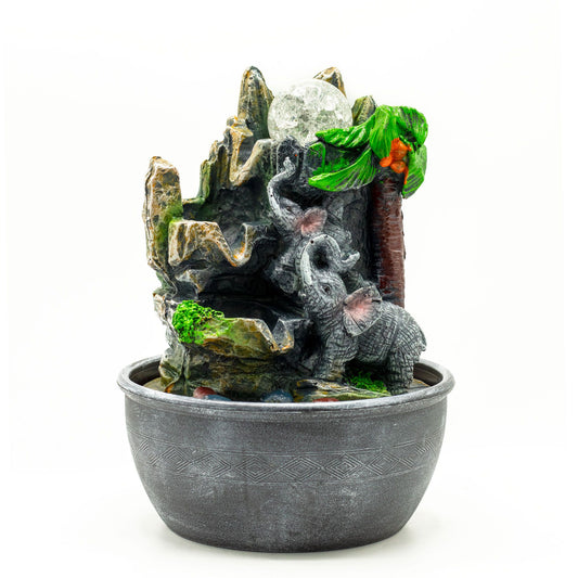 Detailed grey resin tabletop water feature with two elephants standing under a green palm tree with flowing water.