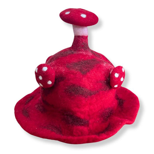 Whimsical red felted hat shaped like a toadstool mushroom with white spots and a wide brim.