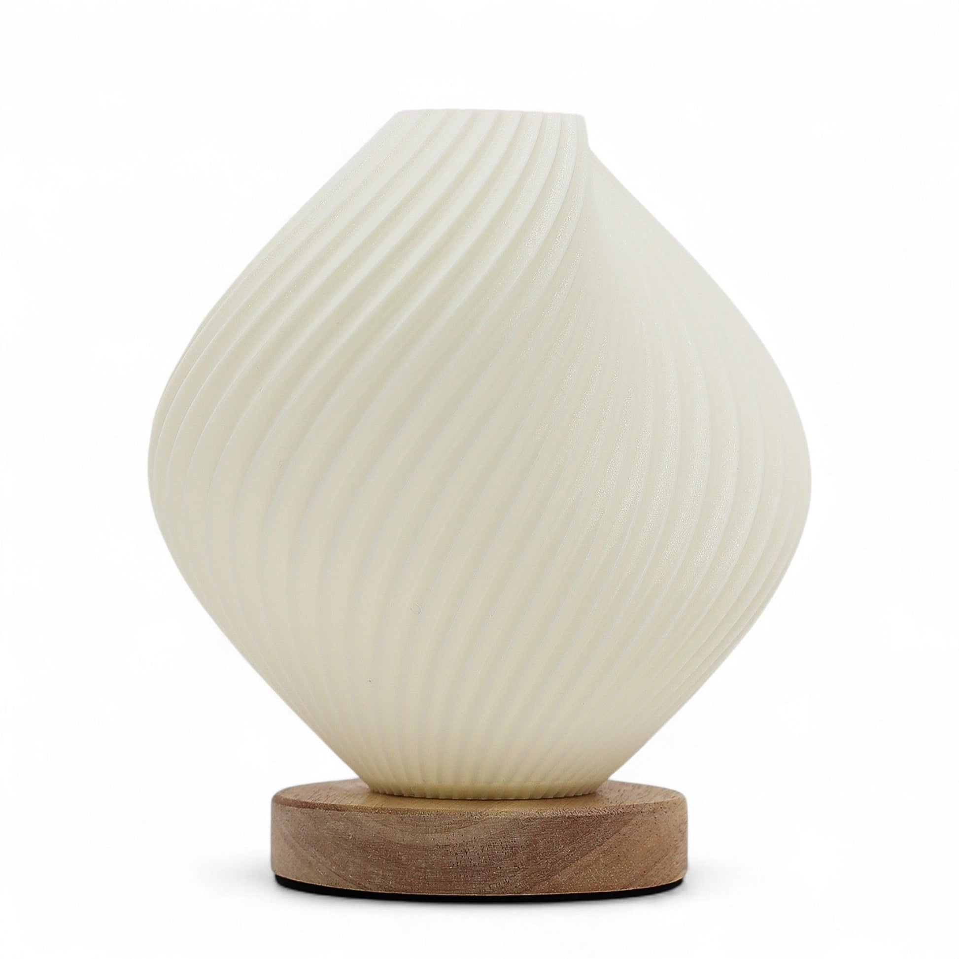 Graceful white spiral lamp with a shell-inspired twisted design emitting a soft warm glow in a modern interior setting.