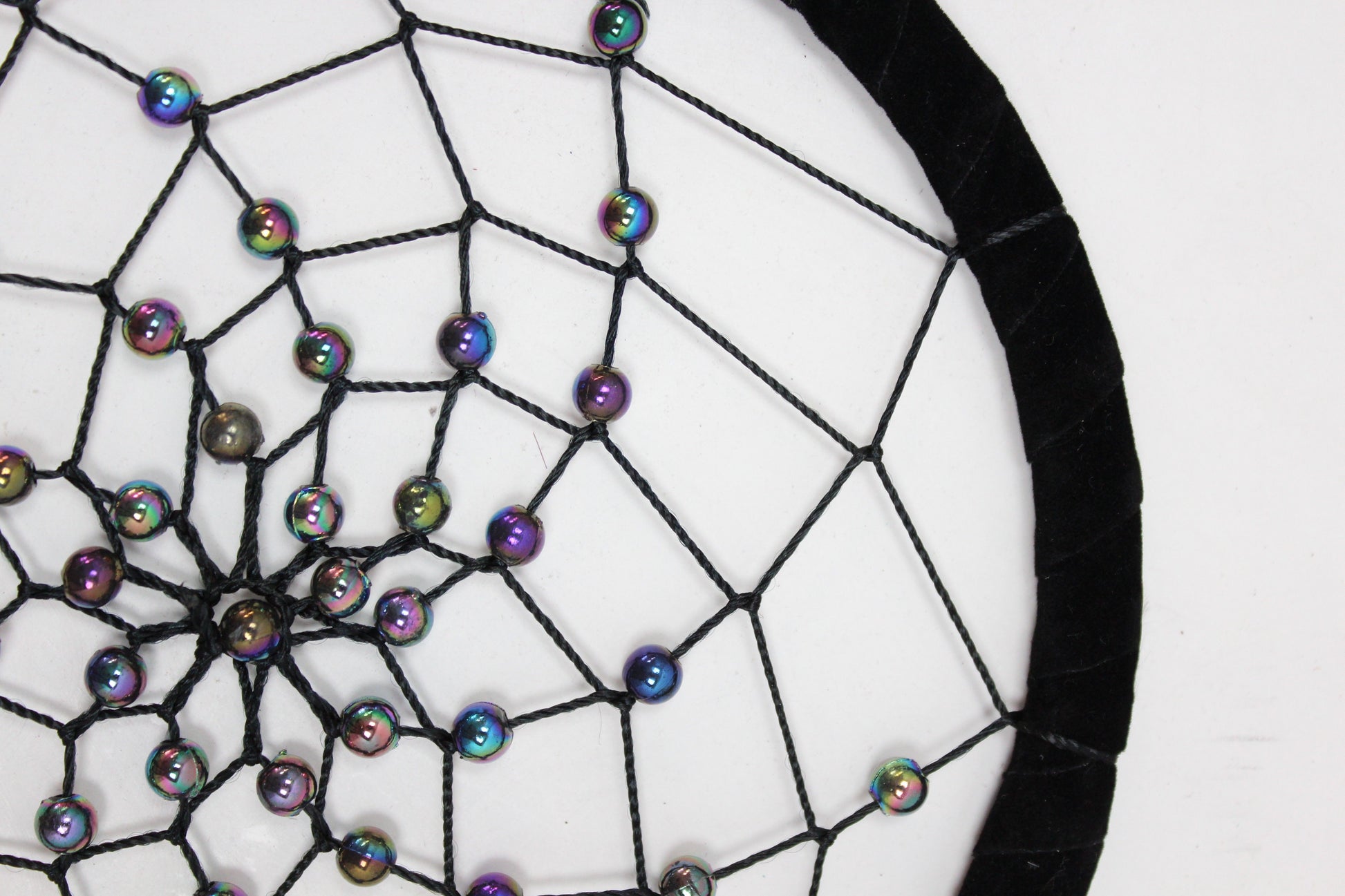 Large round handmade dreamcatcher featuring vibrant turquoise, pink, and purple threads with decorative feathers.