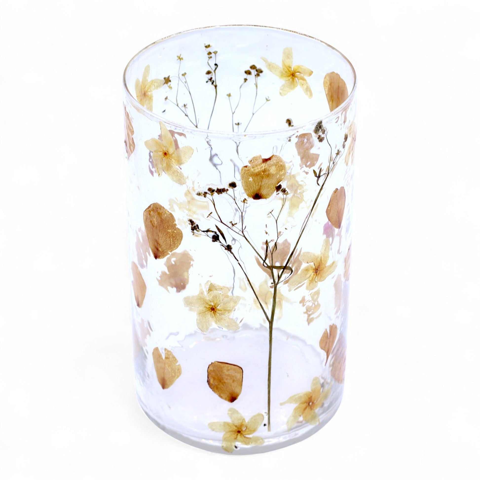 Tall recycled glass candle holder with delicate pink dried flowers embedded inside a cylindrical vase design.