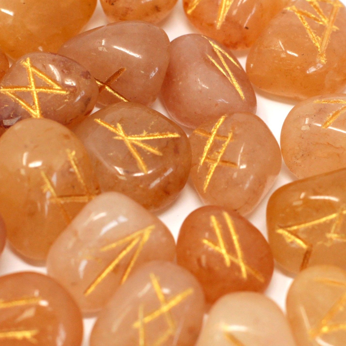Tumbled yellow aventurine stones engraved with traditional rune symbols, displayed with a small drawstring pouch.