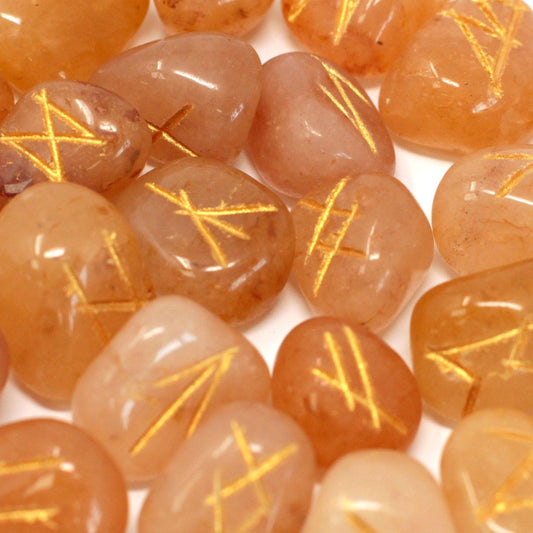 Tumbled yellow aventurine stones engraved with traditional rune symbols, displayed with a small drawstring pouch.