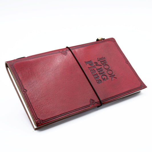 Slim red handmade leather journal featuring an embossed quote and a wrap-around leather tie closure.