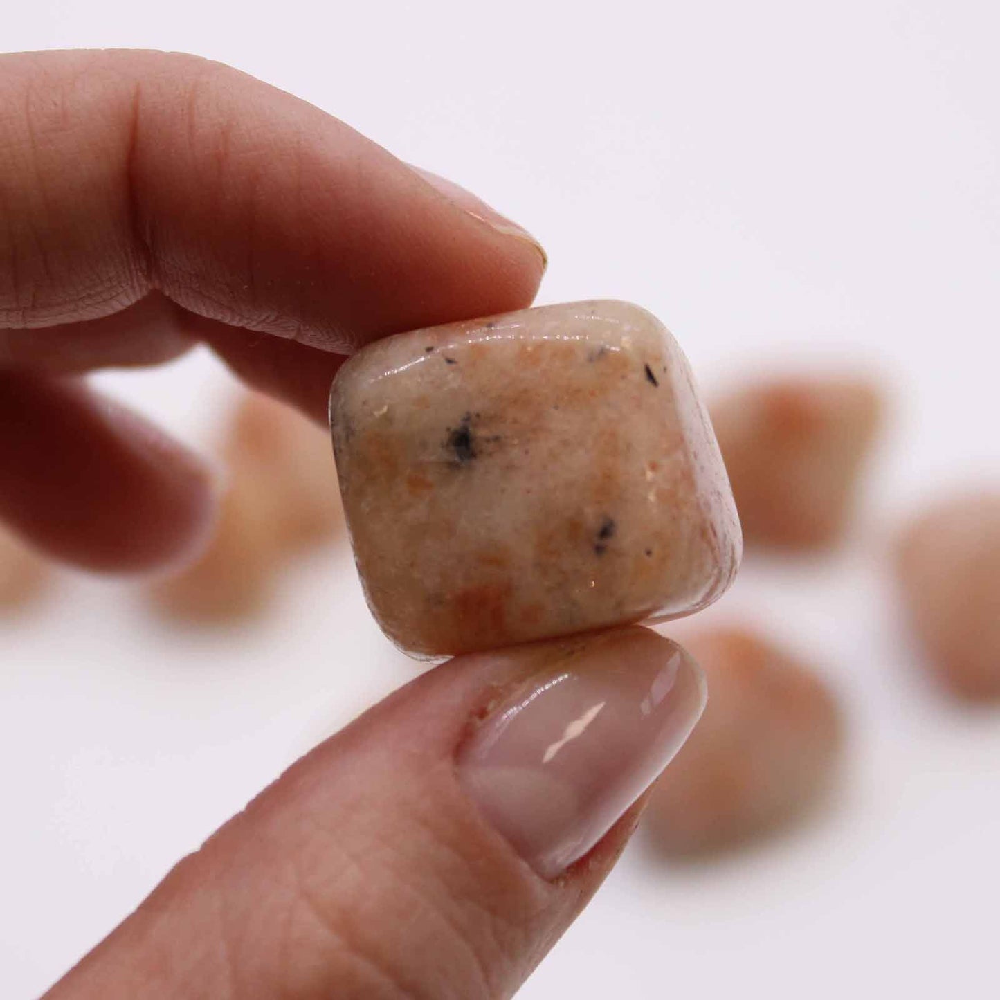 Smooth and polished large sunstone tumble stone with shimmering orange and gold metallic inclusions.