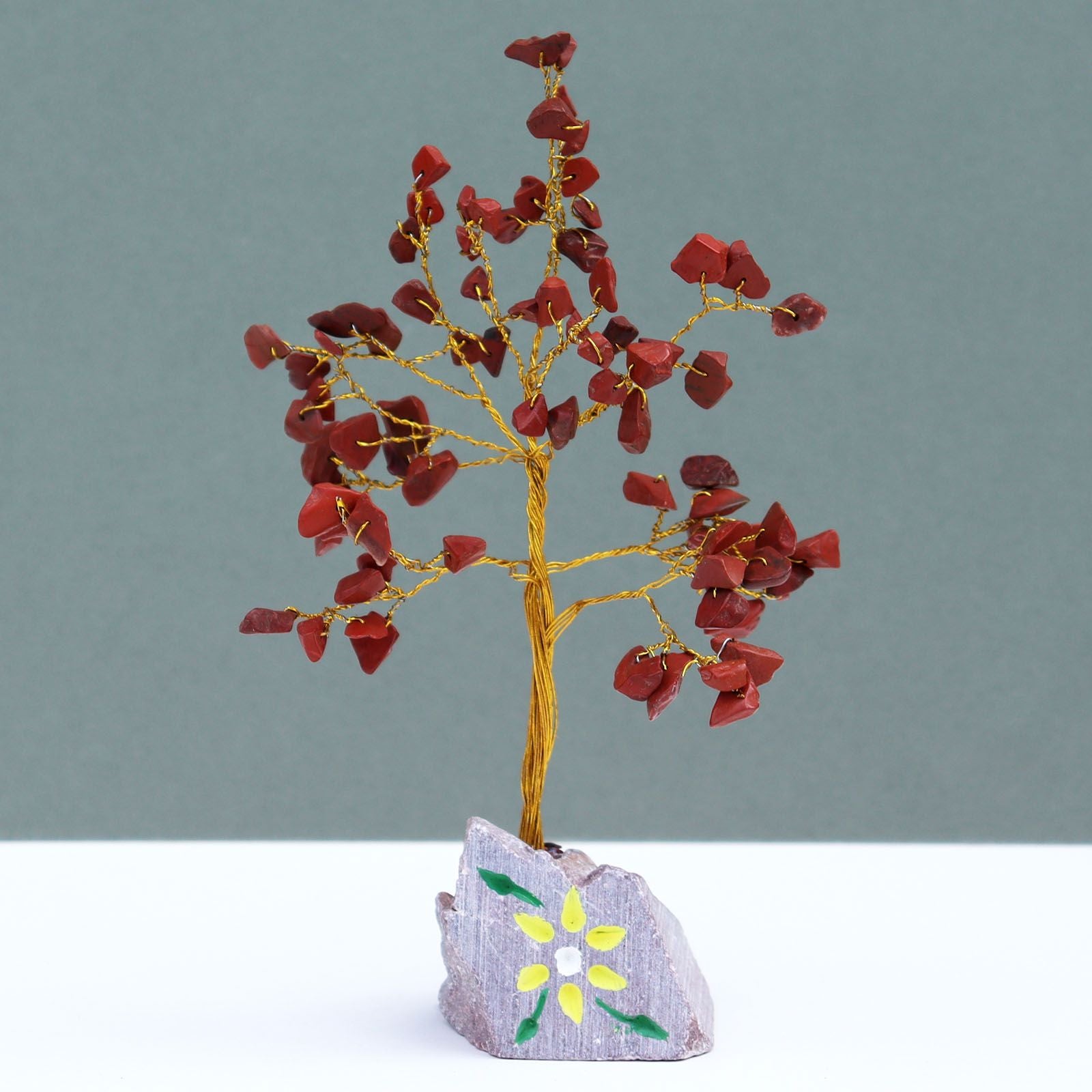 Handcrafted gemstone tree featuring vibrant red jasper leaves and wire branches mounted on a natural stone base.