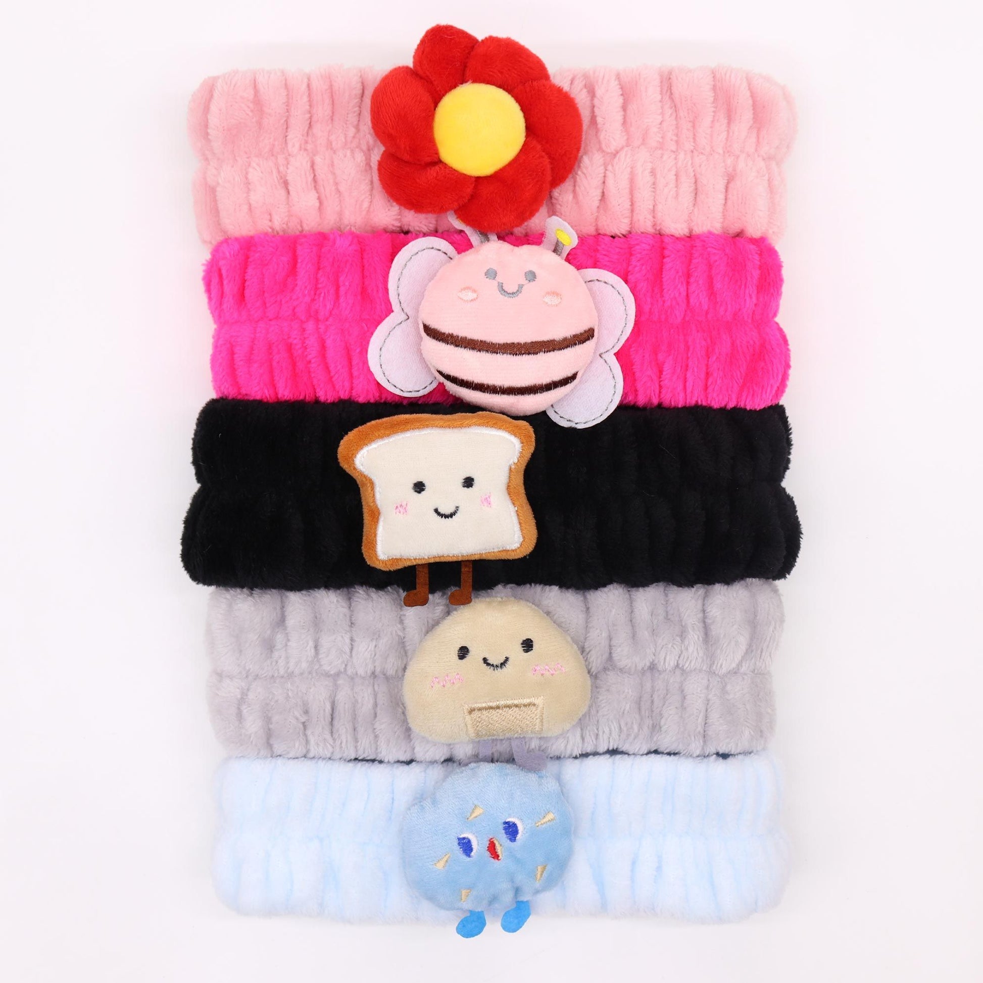 Assorted soft flannel makeup headbands featuring cute characters like smiling toast and playful bees.