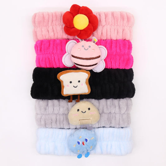 Assorted soft flannel makeup headbands featuring cute characters like smiling toast and playful bees.