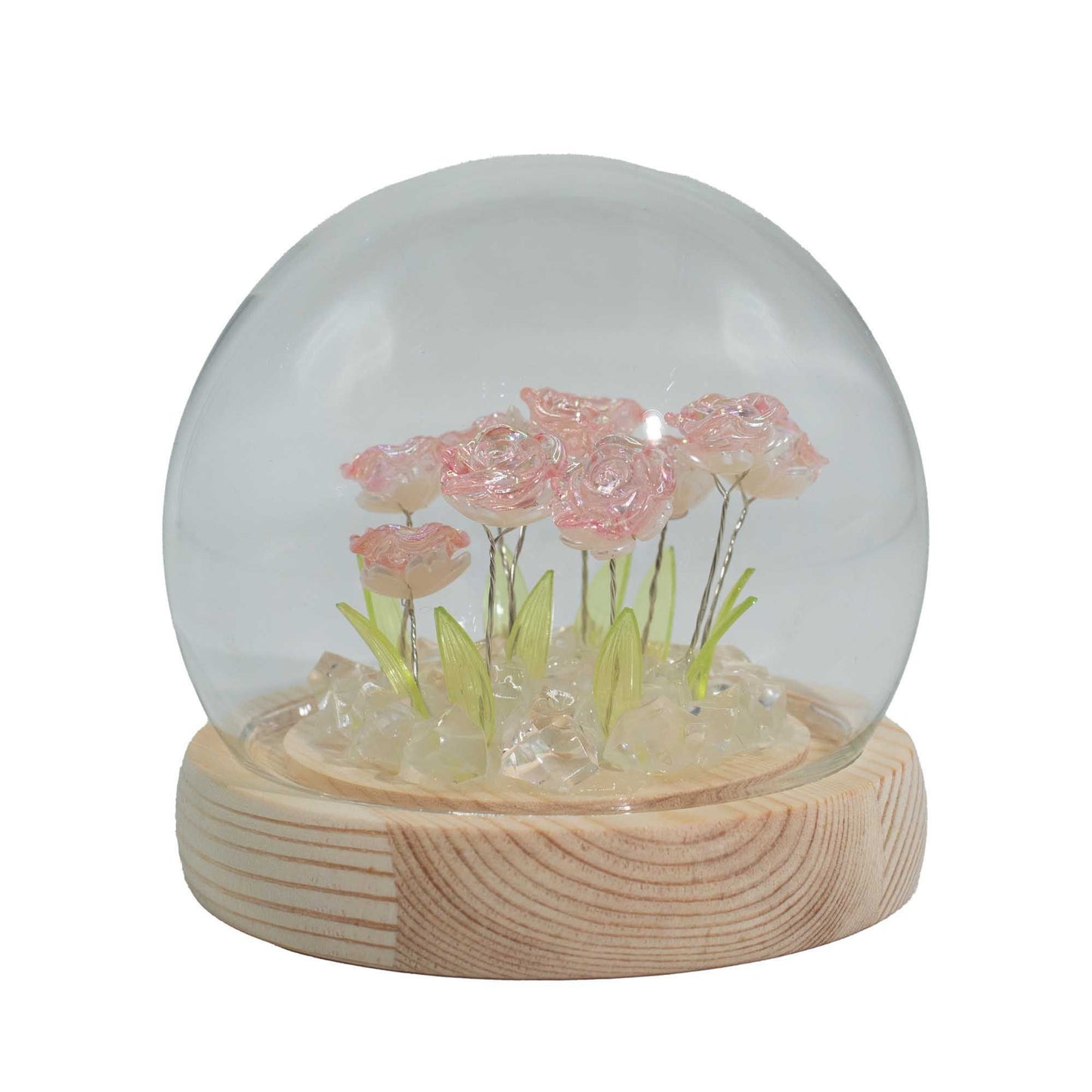 Clear glass dome containing ten pink roses on a natural wooden base, illuminated by warm LED fairy lights.