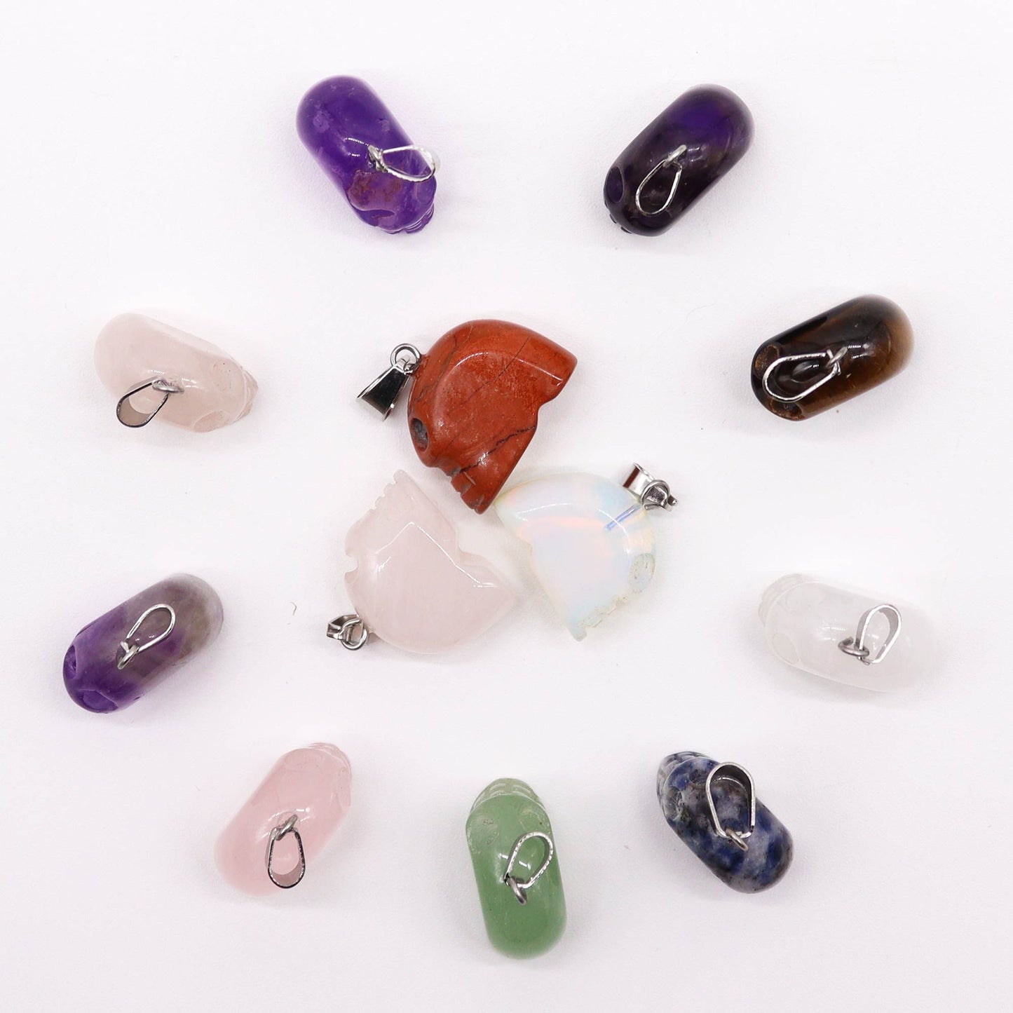 Twelve assorted mini gemstone skull pendants in various natural crystal colours and patterns.