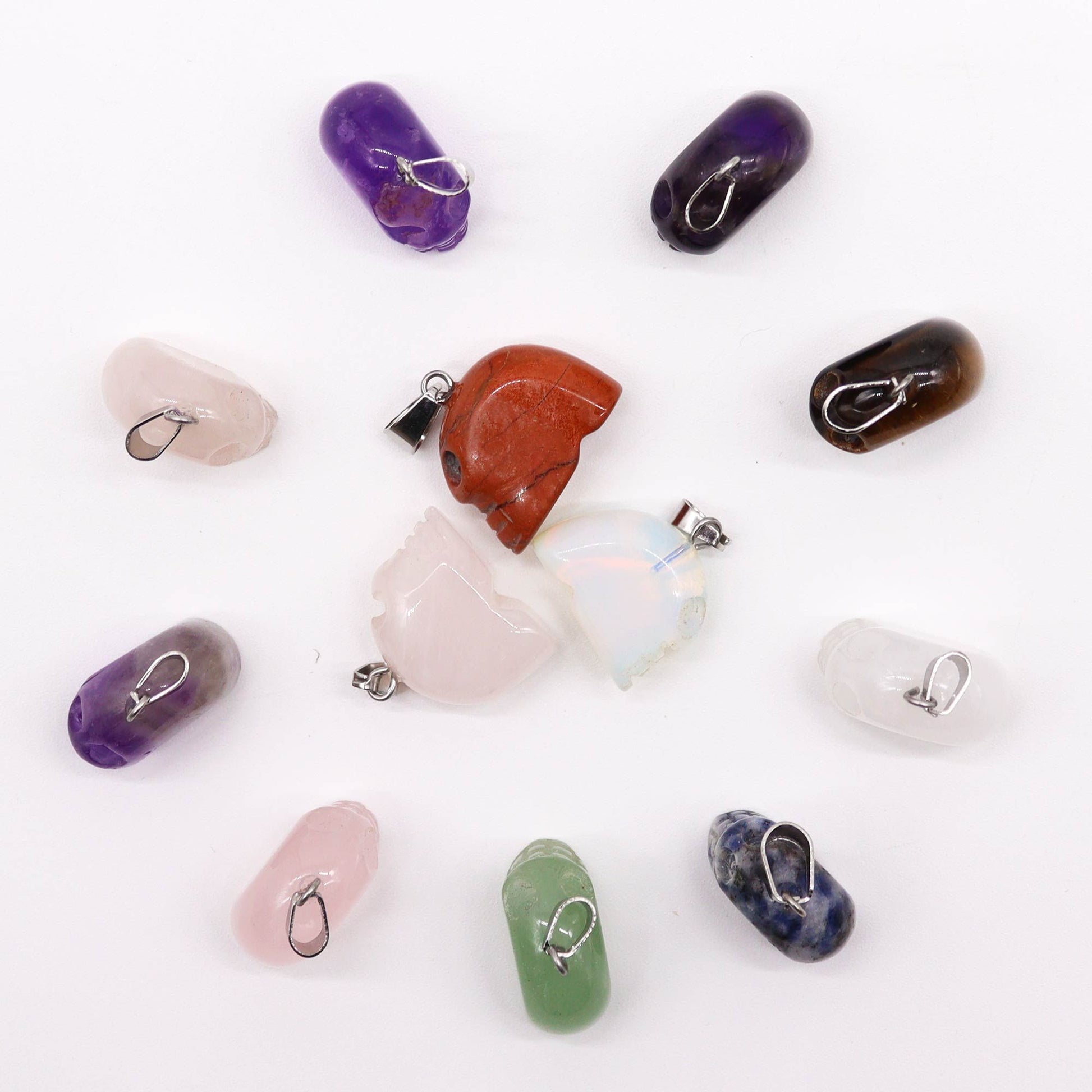Twelve assorted mini gemstone skull pendants in various natural crystal colours and patterns.