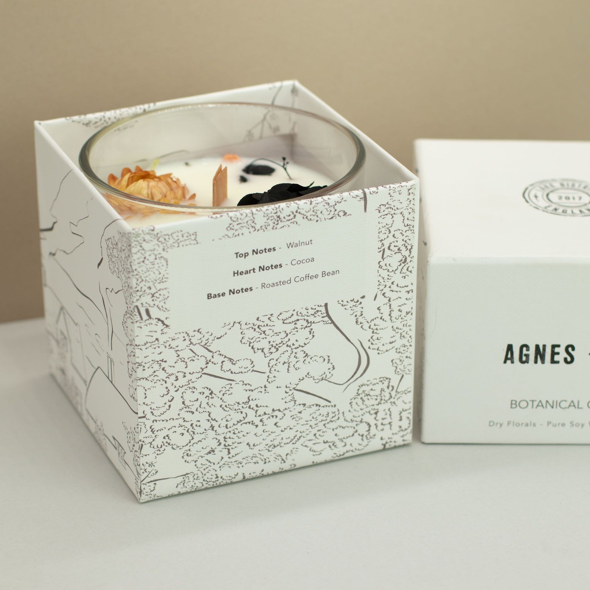 Hand-poured botanical soy wax candle in a glass jar decorated with natural dried petals and coffee beans.
