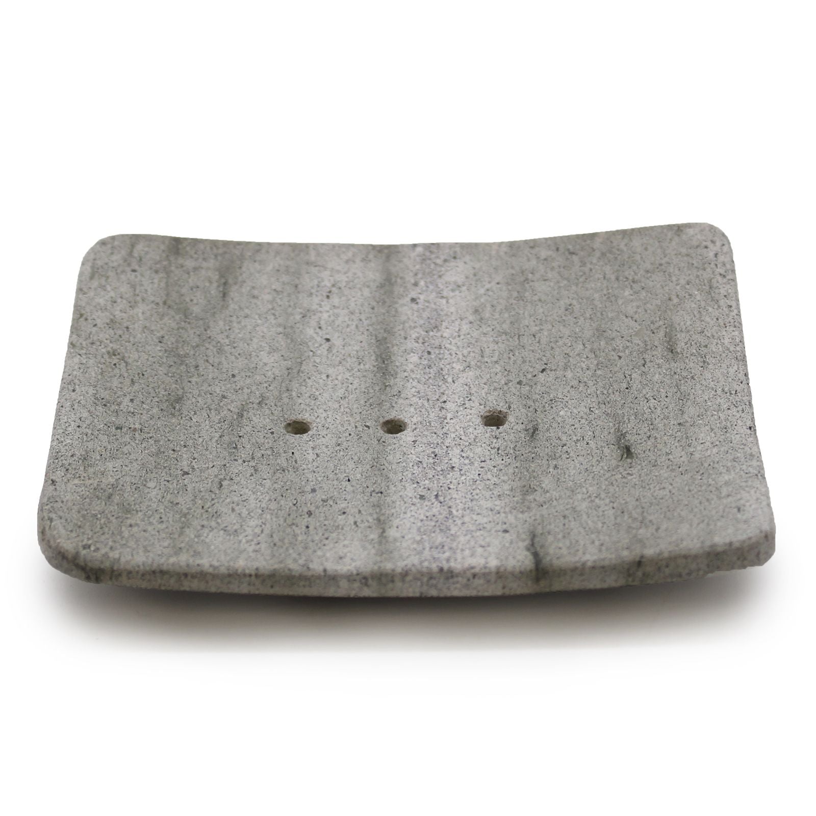 Minimalist square grey stone soap dish with four drainage holes on a clean surface.