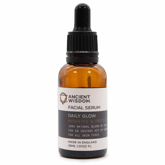 Clear glass bottle of golden facial serum oil with a dropper top on a clean white background.
