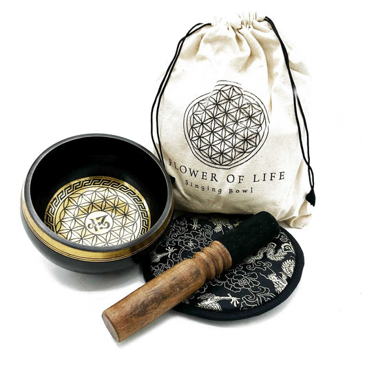 Hand-beaten brass singing bowl with intricate Flower of Life engravings, resting on a decorative cushion with a wooden mallet