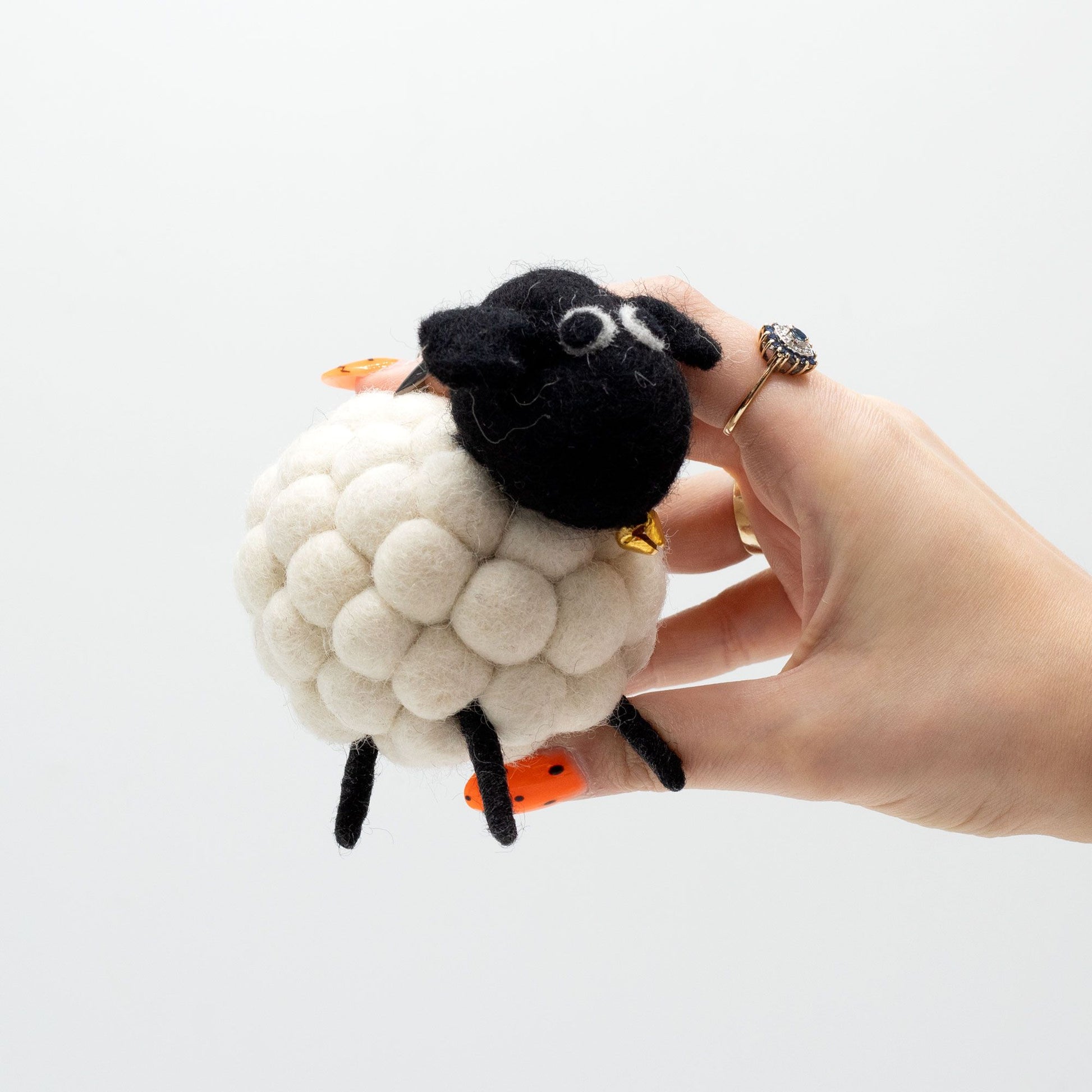 Handmade white felt sheep with a soft fluffy texture and a small golden bell on a red collar.