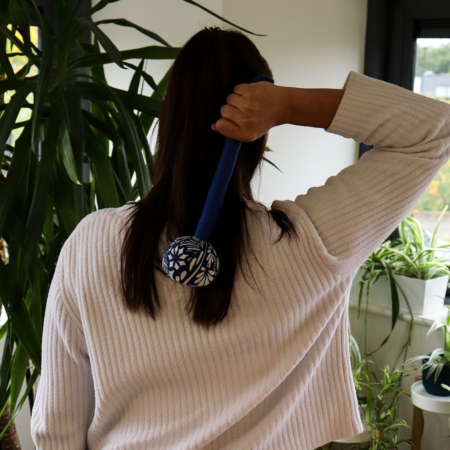 Blue fabric massage hammer with a bamboo handle, filled with natural herbs for muscle relief and relaxation.