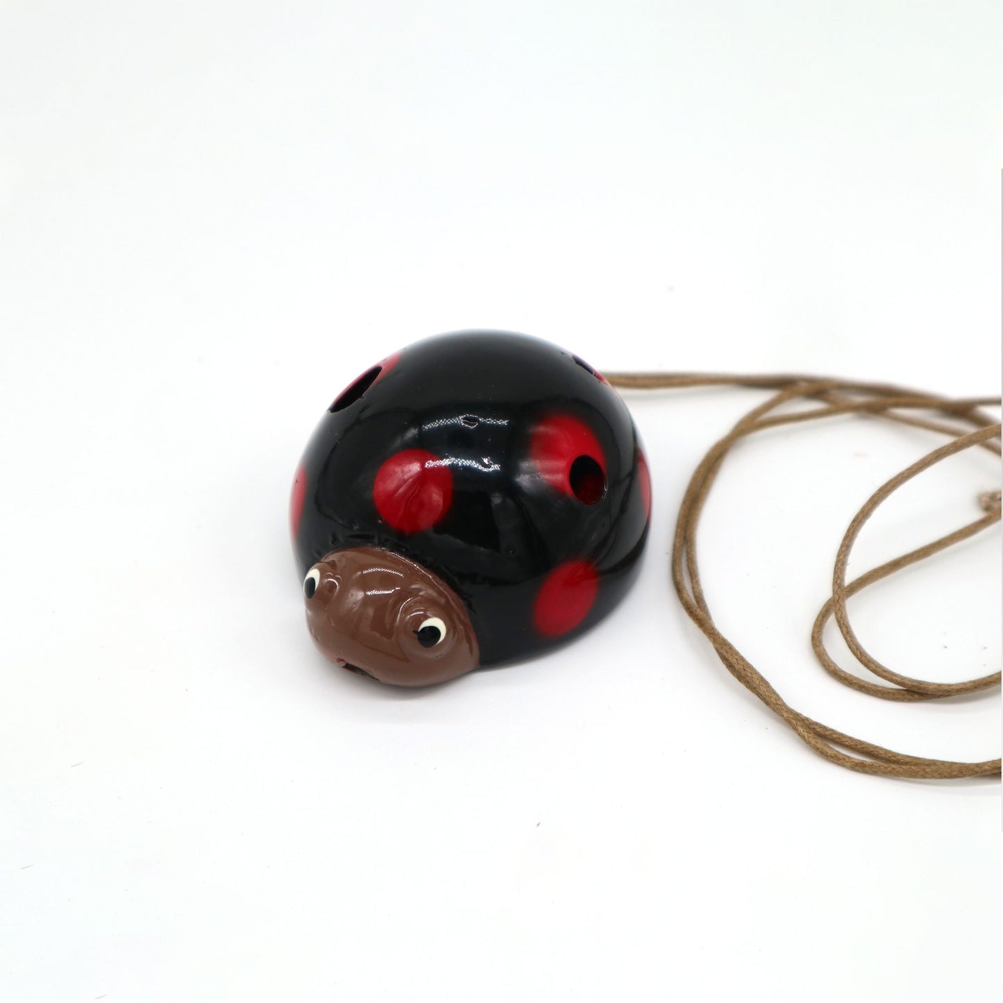 Handcrafted ceramic ladybird ocarina with a vibrant red and black spotted finish and multiple finger holes.