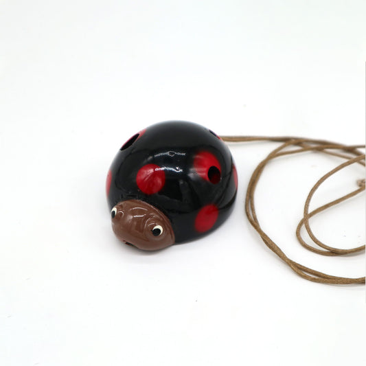Handcrafted ceramic ladybird ocarina with a vibrant red and black spotted finish and multiple finger holes.