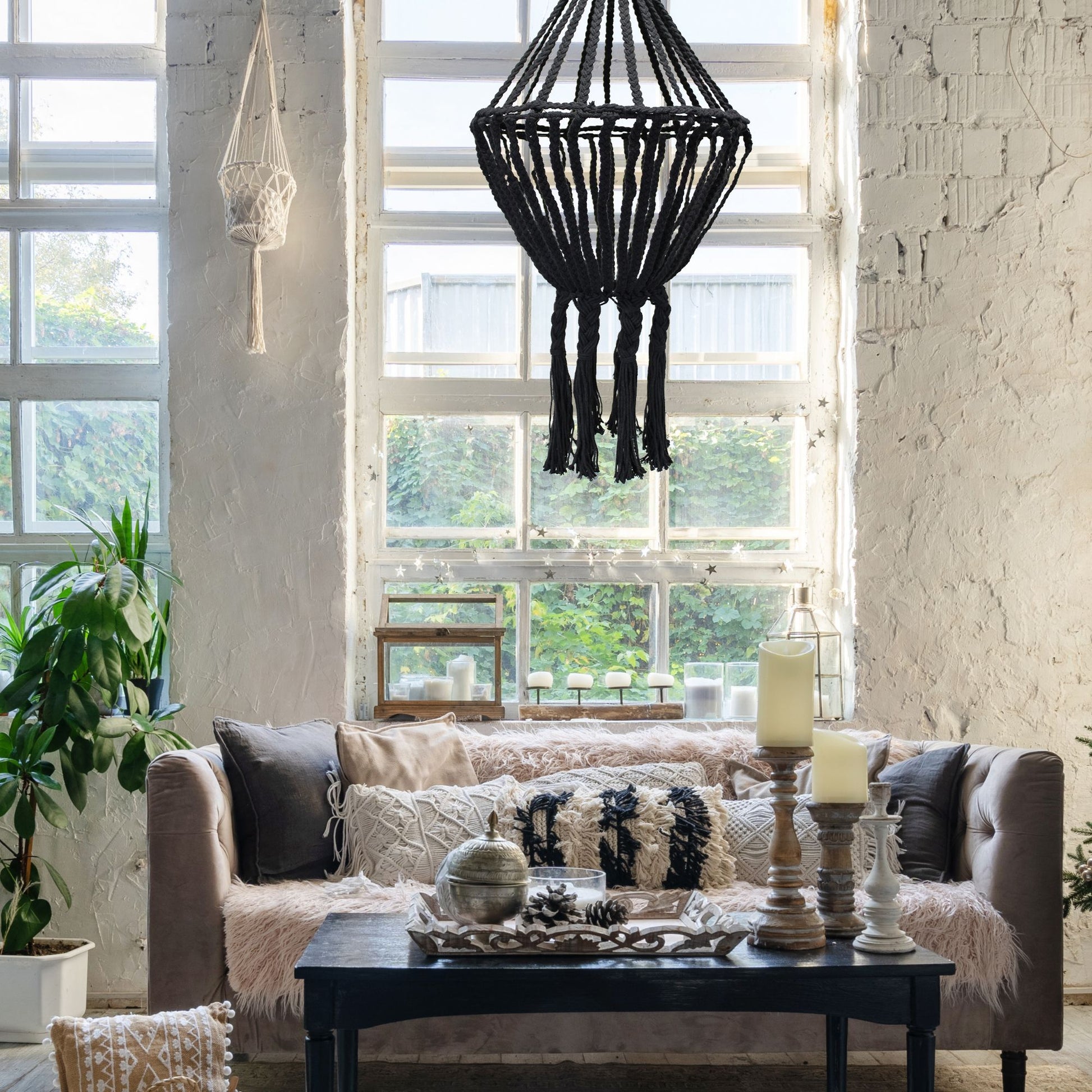 Large hand-woven black macrame chandelier with a cascading drop design hanging in a modern interior.