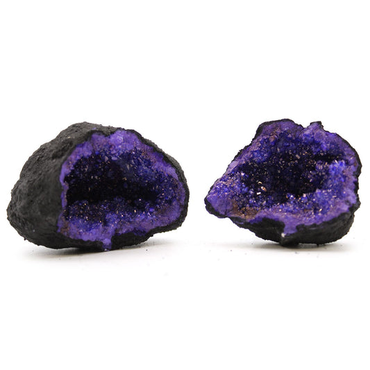 A split open black rock geode revealing vibrant turquoise and purple dyed calcite crystals inside.