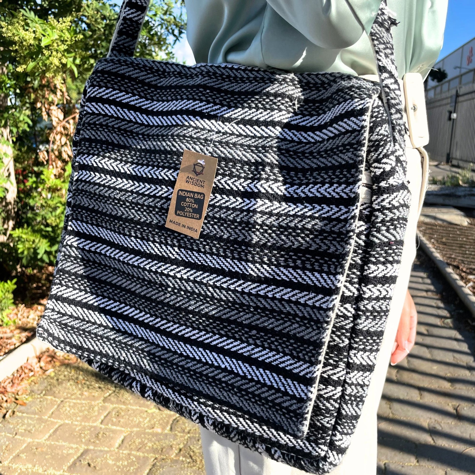 Hand-woven grey and white striped fabric laptop bag with a soft padded texture and simple flap closure.