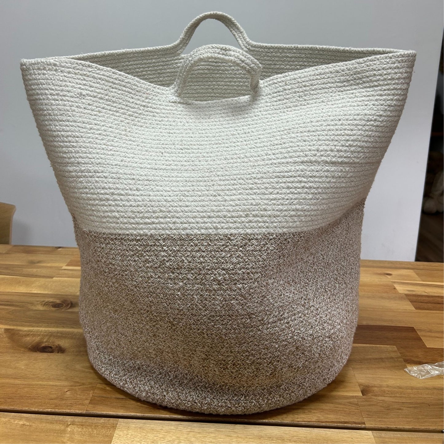 Large circular woven cotton rope storage basket in a neutral beige colour with integrated handles.