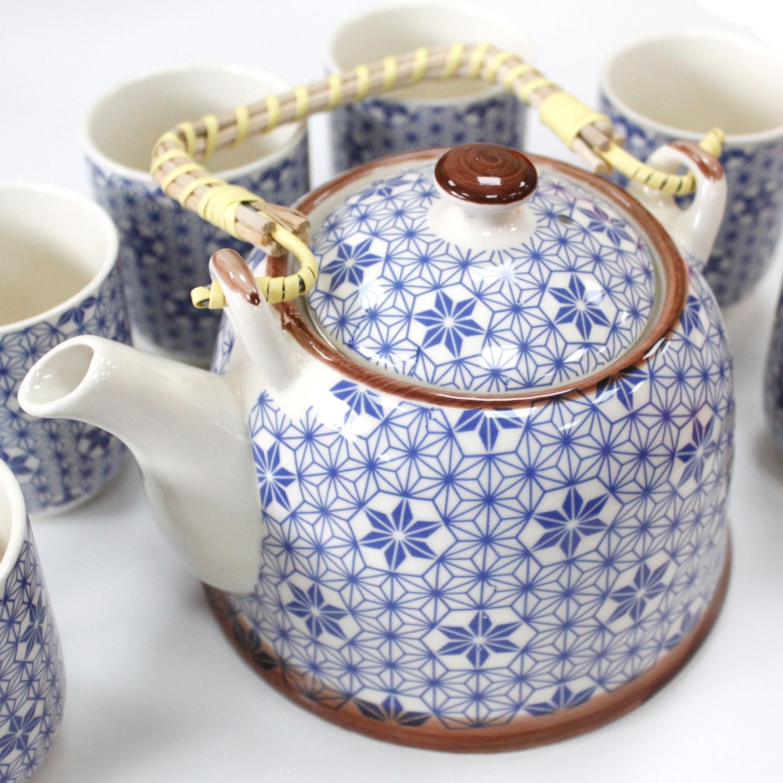 Elegant blue ceramic teapot featuring a white star pattern, complete with a metal strainer lid and matching small cups.