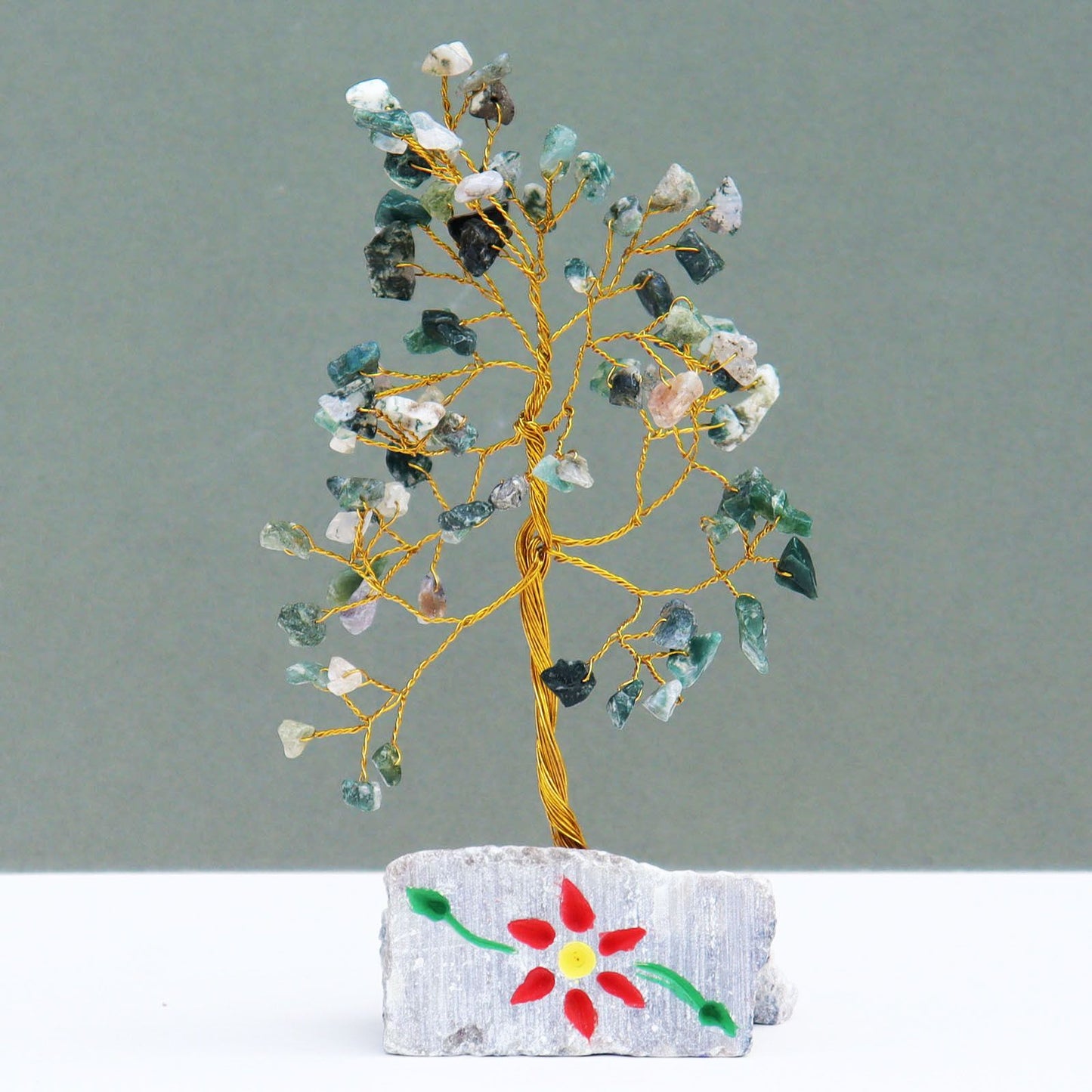 Handmade gemstone tree featuring green moss agate leaves on twisted wire branches set on a natural stone rock base.