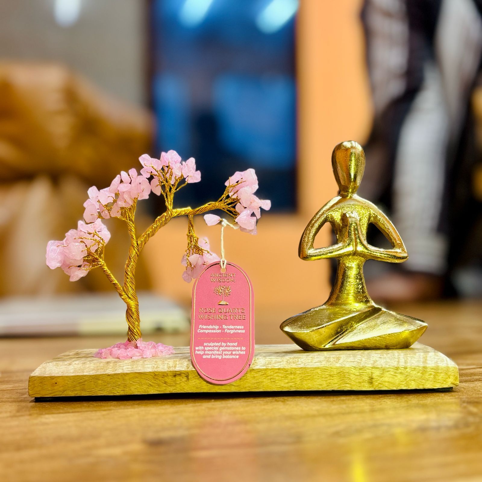 Handcrafted Rose Quartz gemstone tree with golden wire branches on a base featuring a figure in Namaste yoga pose.