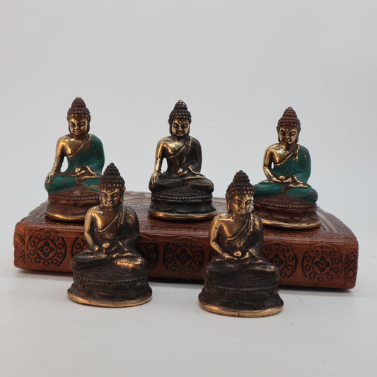 Small polished brass statue of a Buddha sitting in a meditative pose with detailed engravings.