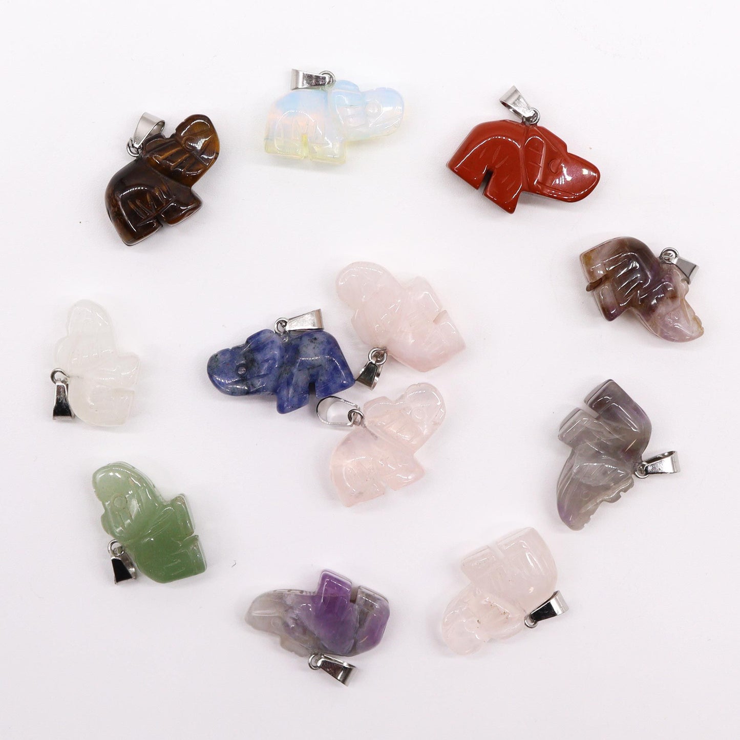 Twelve assorted colourful gemstone pendants carved into the shape of small lucky elephants with trunks raised.