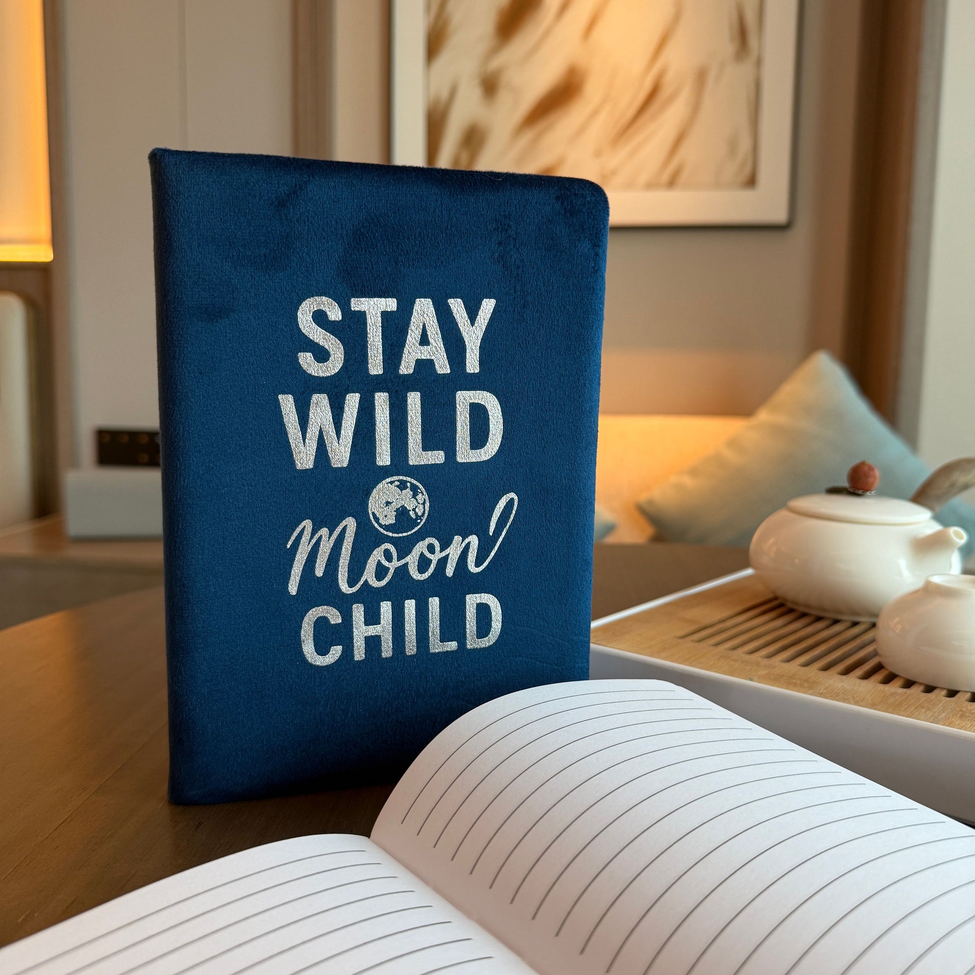 Dark blue velvet notebook with silver embossed Stay Wild Moon Child text and celestial stars.