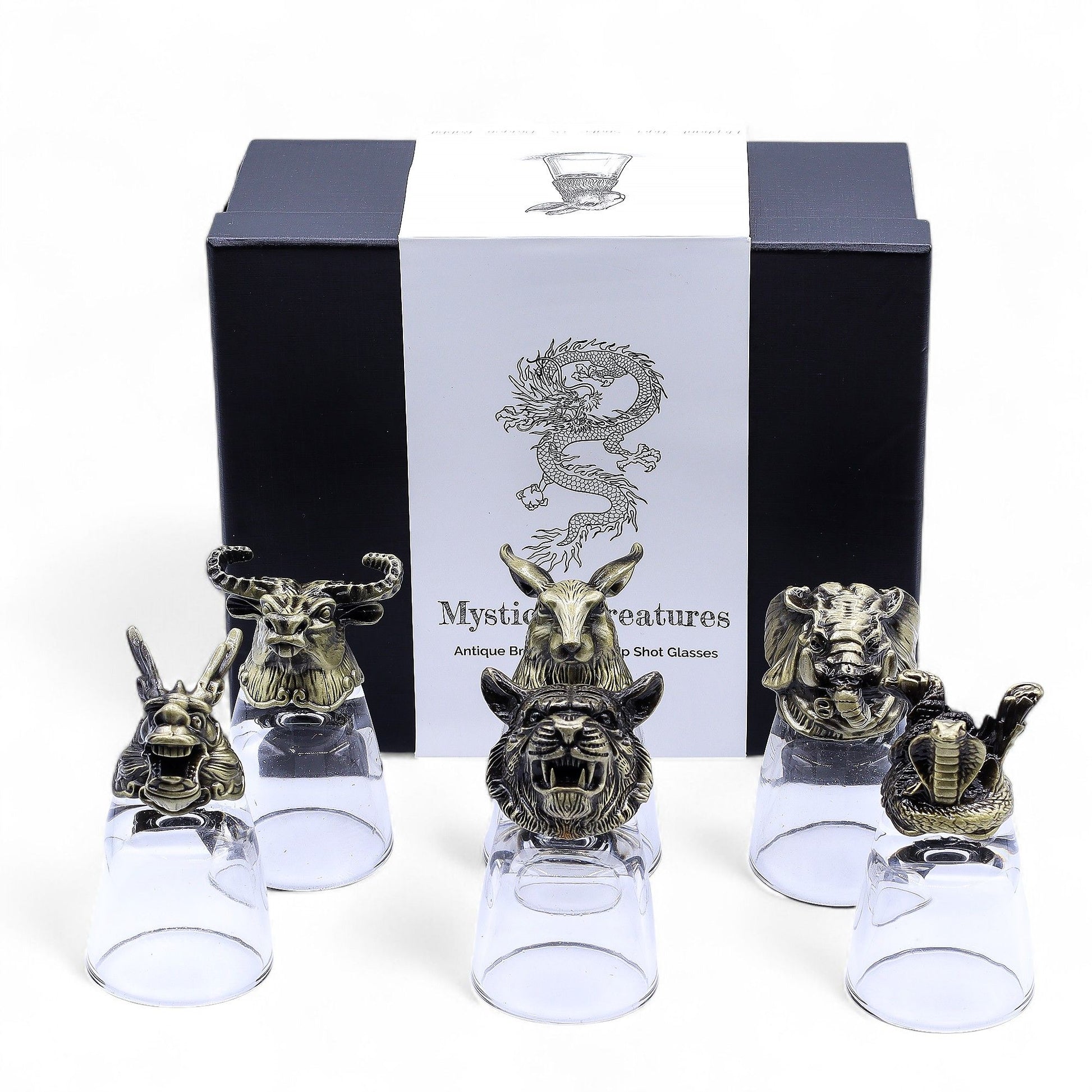 Six clear shot glasses set on ornate antique bronze bases featuring detailed mystical creatures.