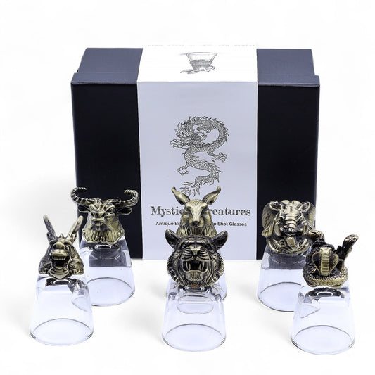 Six clear shot glasses set on ornate antique bronze bases featuring detailed mystical creatures.