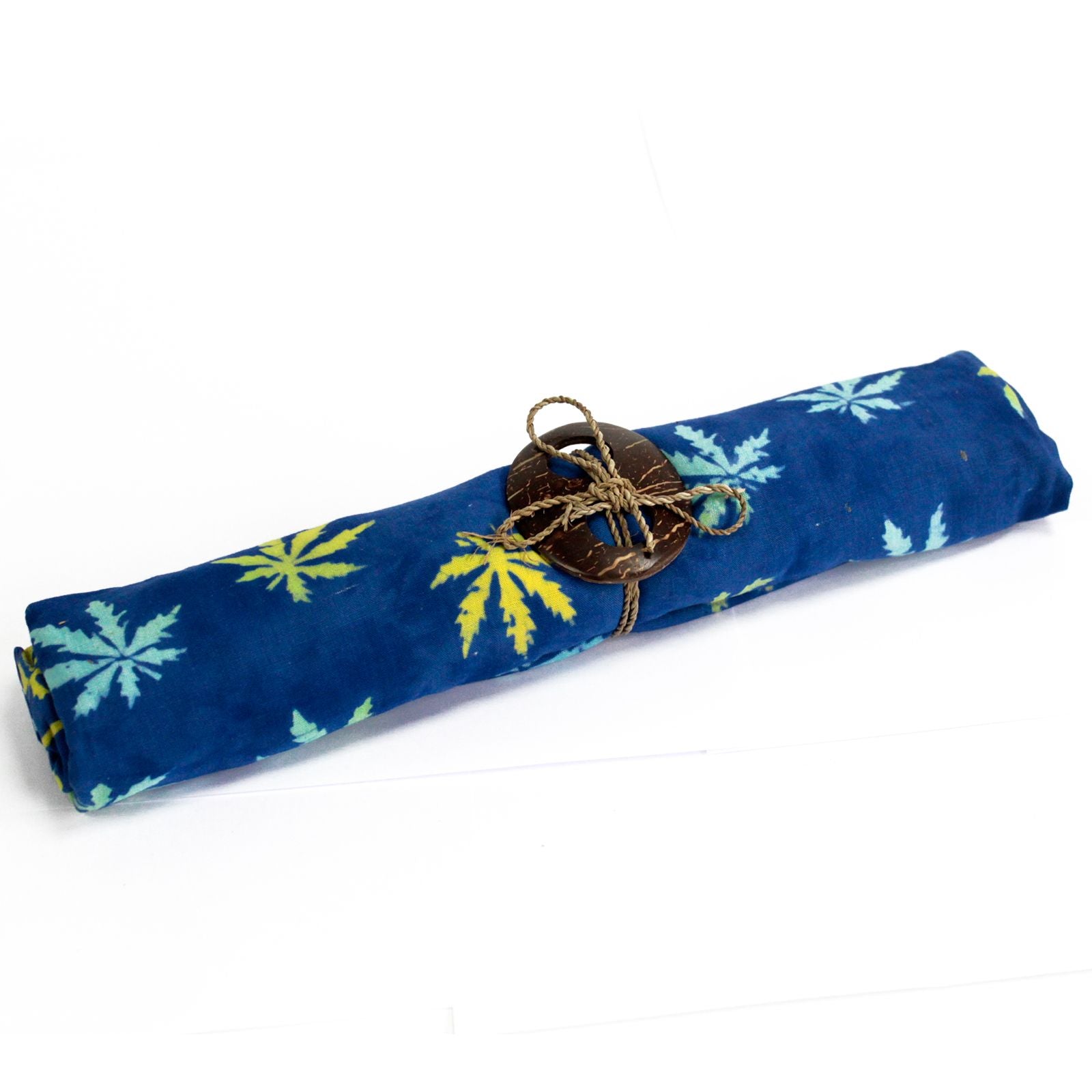 Handcrafted blue sarong featuring a white tropical leaf block print pattern and a decorative coconut shell buckle.