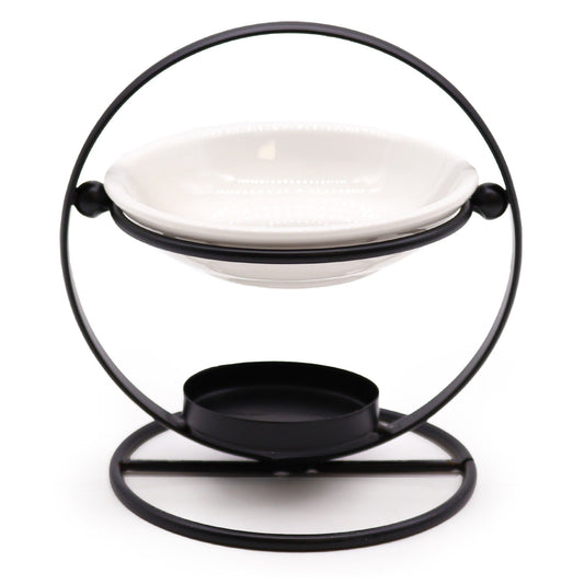 Minimalist round ceramic oil burner bowl resting on a sleek black metal geometric stand.