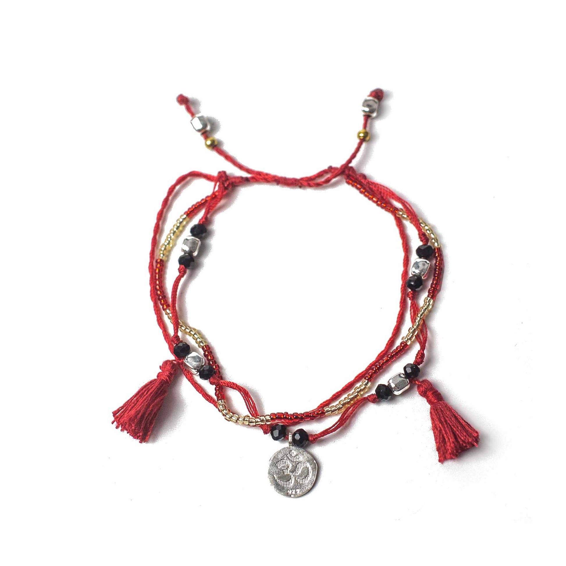 Intricate temple string bracelet with decorative silver beads and a symbolic silver charm on a woven cord.
