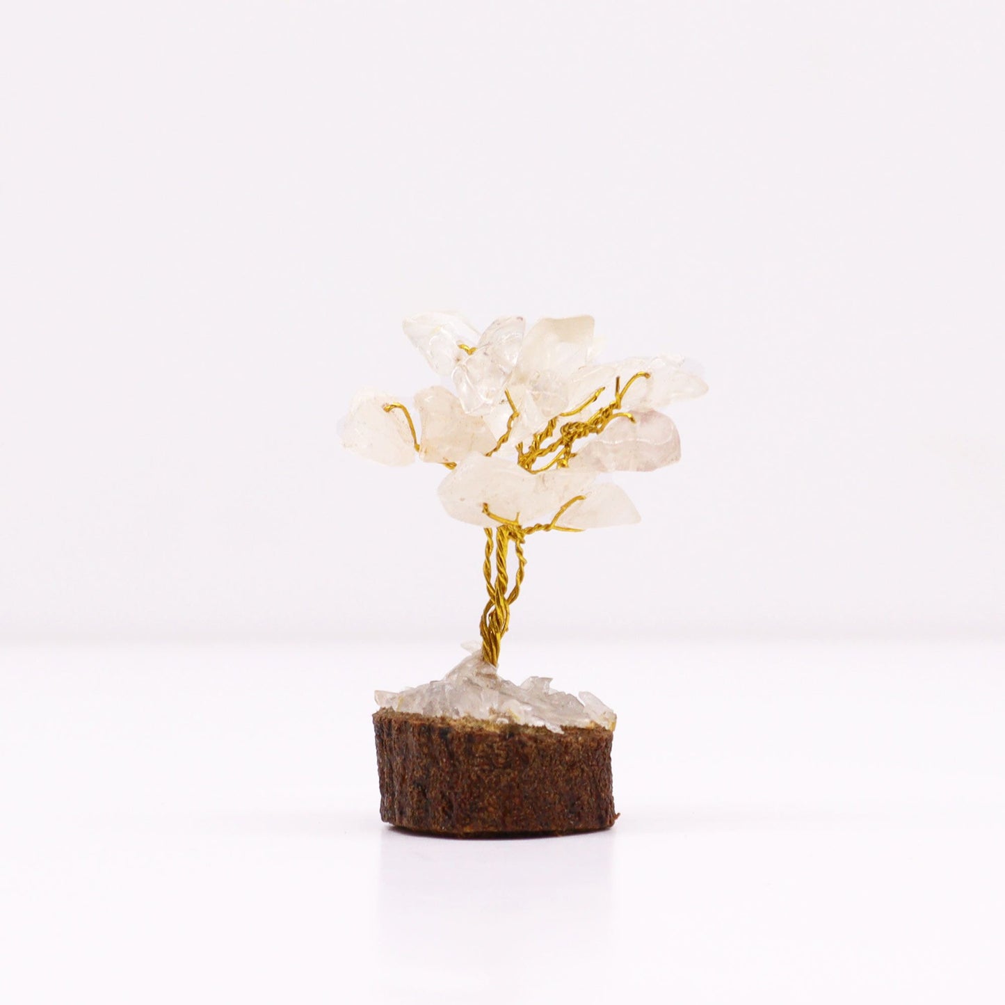 Miniature gemstone tree with clear rock quartz crystal chips on wire branches, mounted on a natural round wooden base.